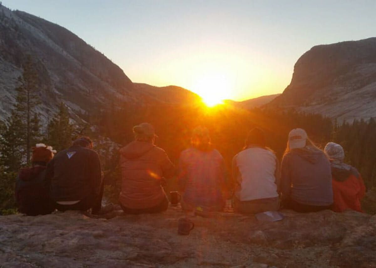 Backpackers enjoying sunset in Yosemite while sitting on a bluff.