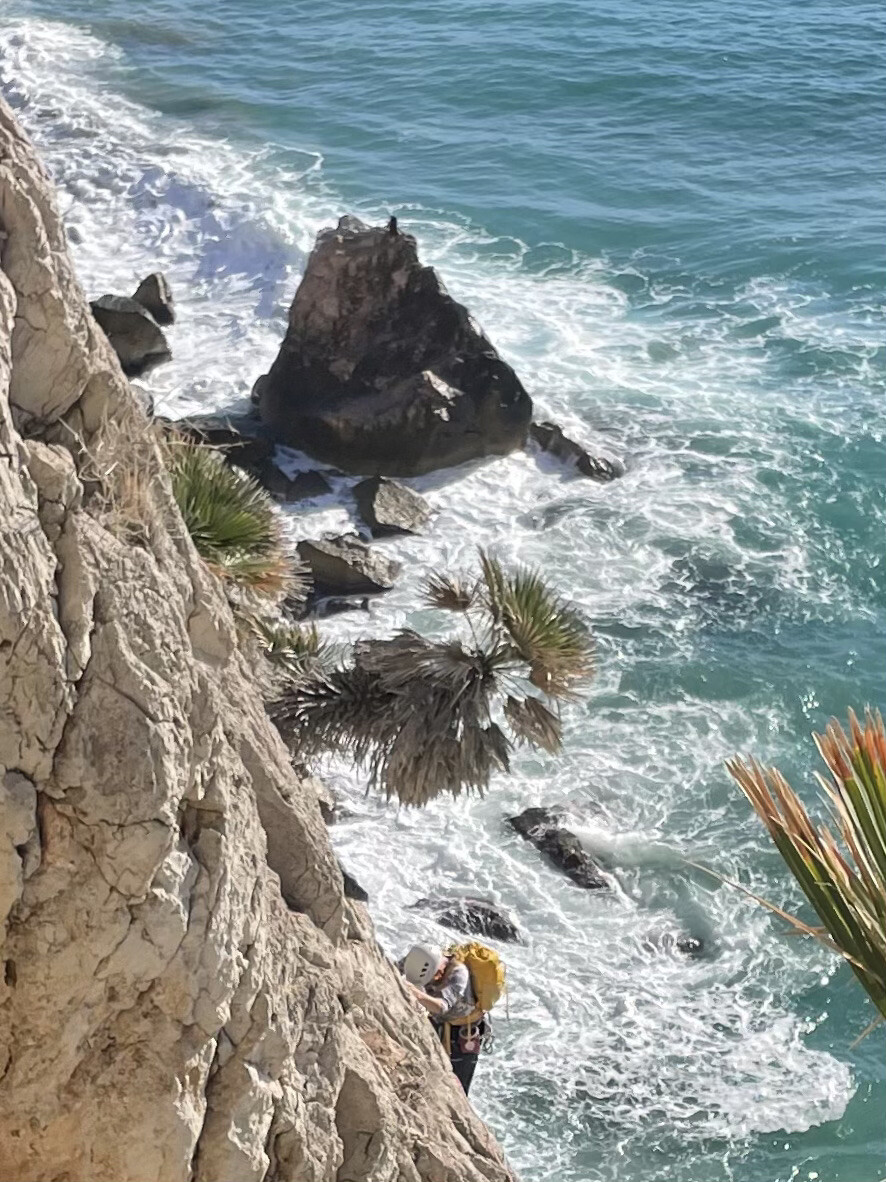 Rock climber scaling cliff above a river