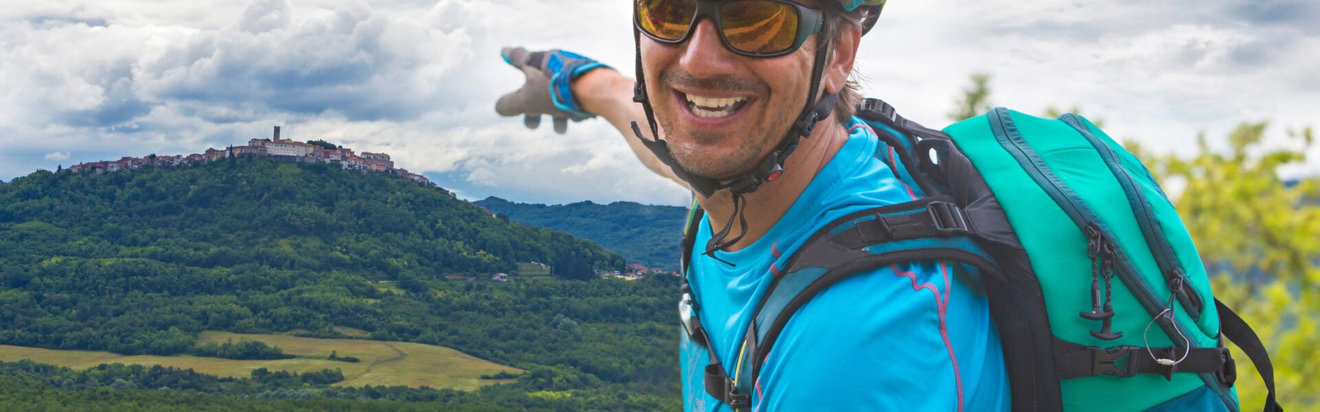 A cyclist pointing at the medieval hilltop town of Motovun while located in the verdant Mirna Valley in Istria, Croatia.
