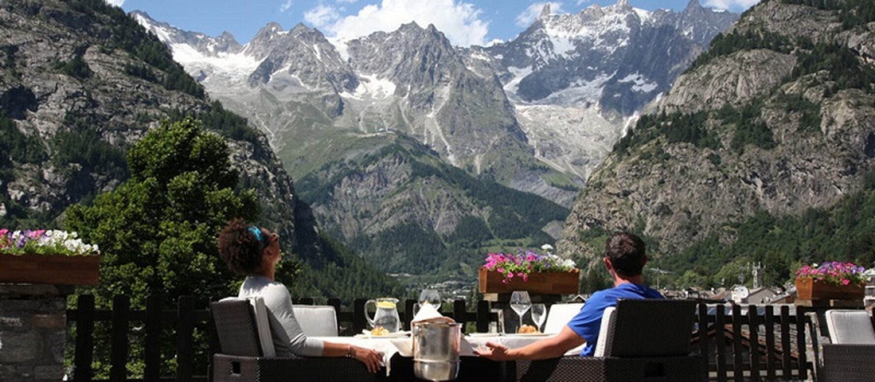 A couple enjoying a dinner in a hotel in Courmayeur, with a view of Alpine peaks.
