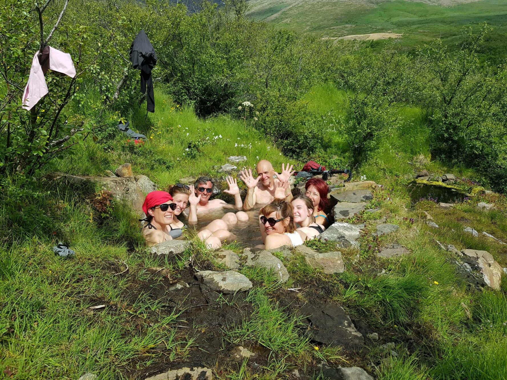 Hikers enjoying a natural geothermal hot spring in the Icelandic wilderness.
