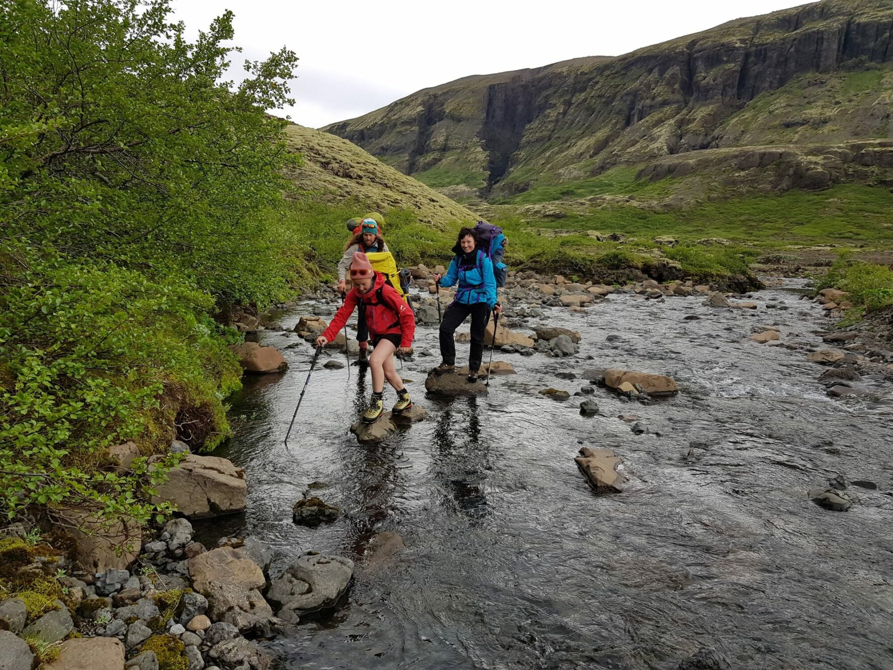 Hikers crossing a river in the Icelandic wilderness.