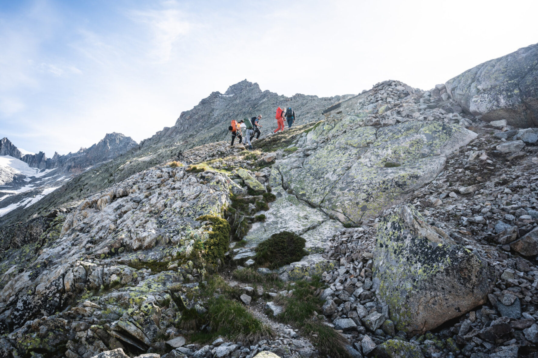 Hikers navigating rugged, rocky terrain in the Swiss Alps along the Four Springs Trek.