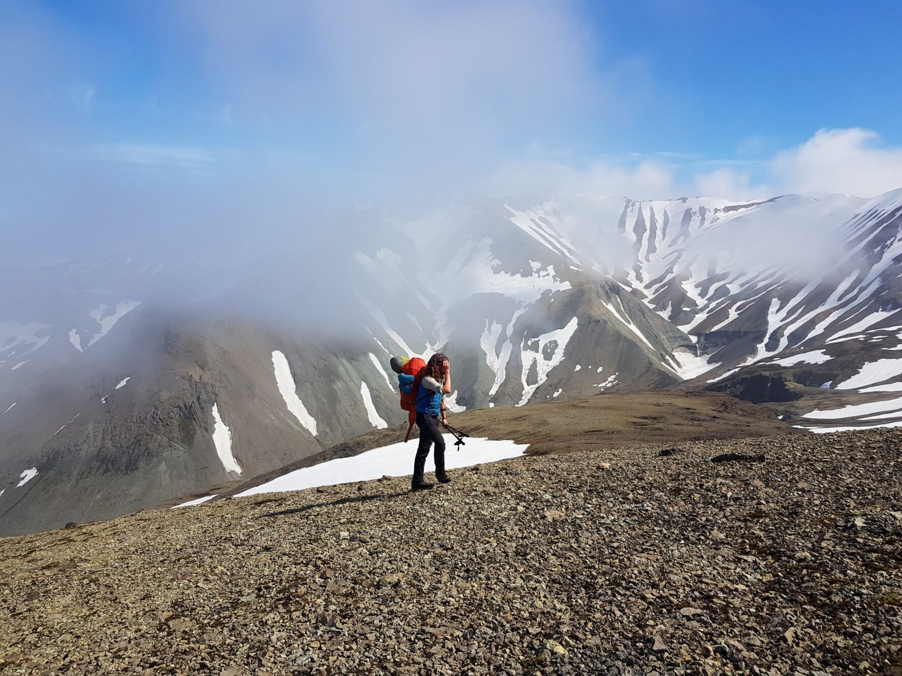 Hiker in the Skaftafell Mountains, famous for their multi-colored rhyolite rock formations.