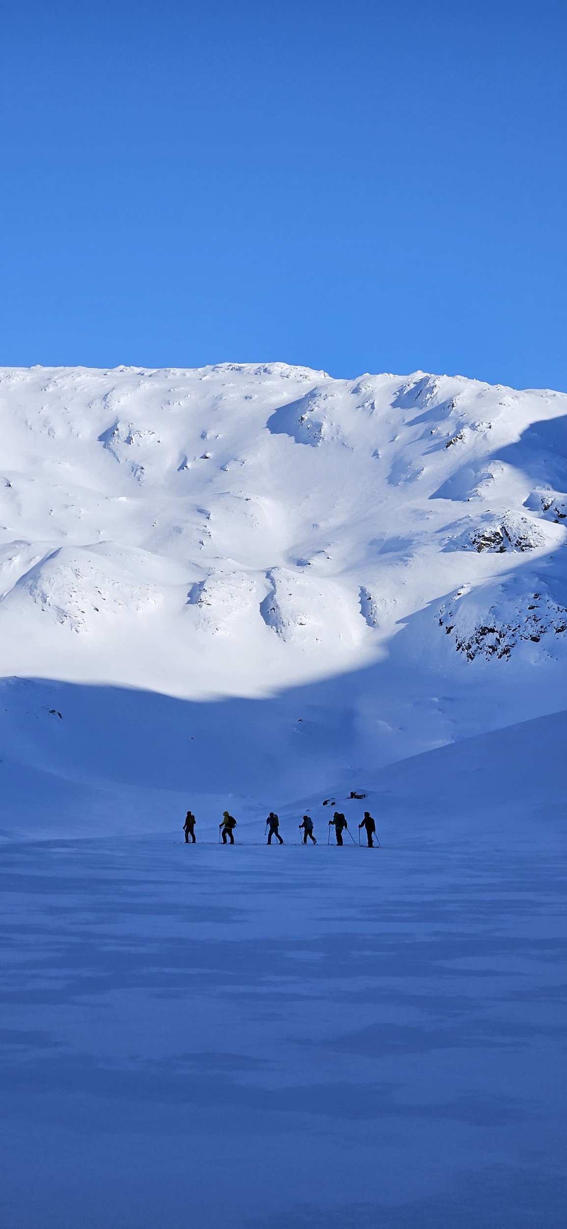 Skiers in a shade of a mountain, skiing