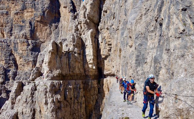 A group of via ferrata enthusiasts walking an exciting via ferrata in the Dolomites