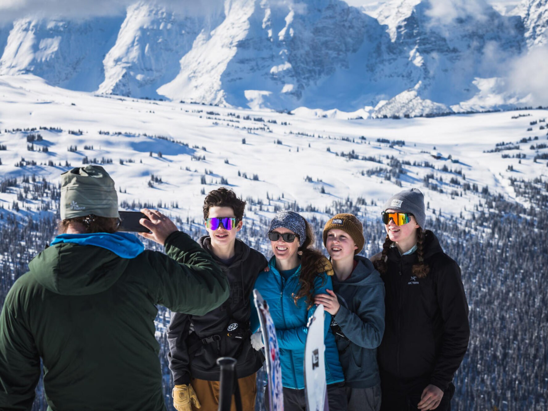 Family posing for a photo near the Purcell Mountain Lodge in British Columbia during their ski touring trip.