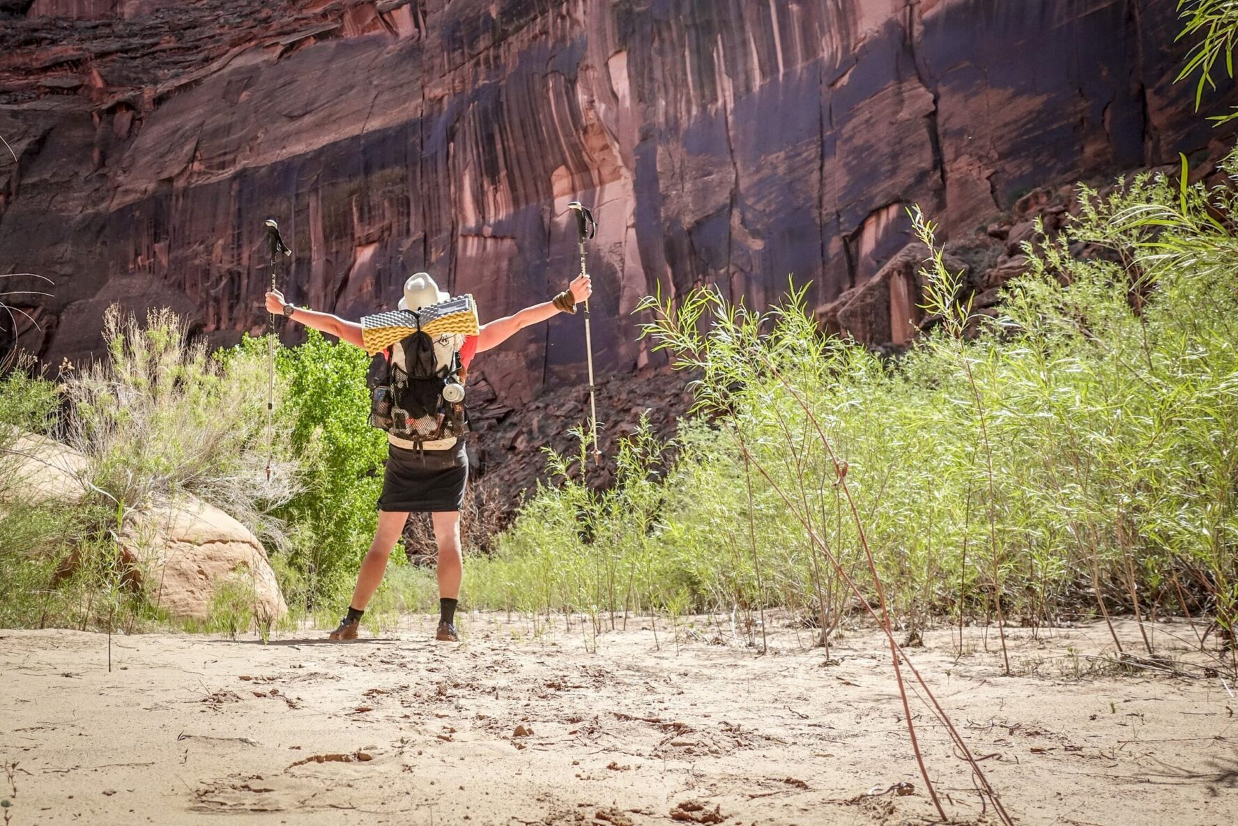 A proud backpacker near a red sandstone rock formation, Coyote. Gulch, Utah.