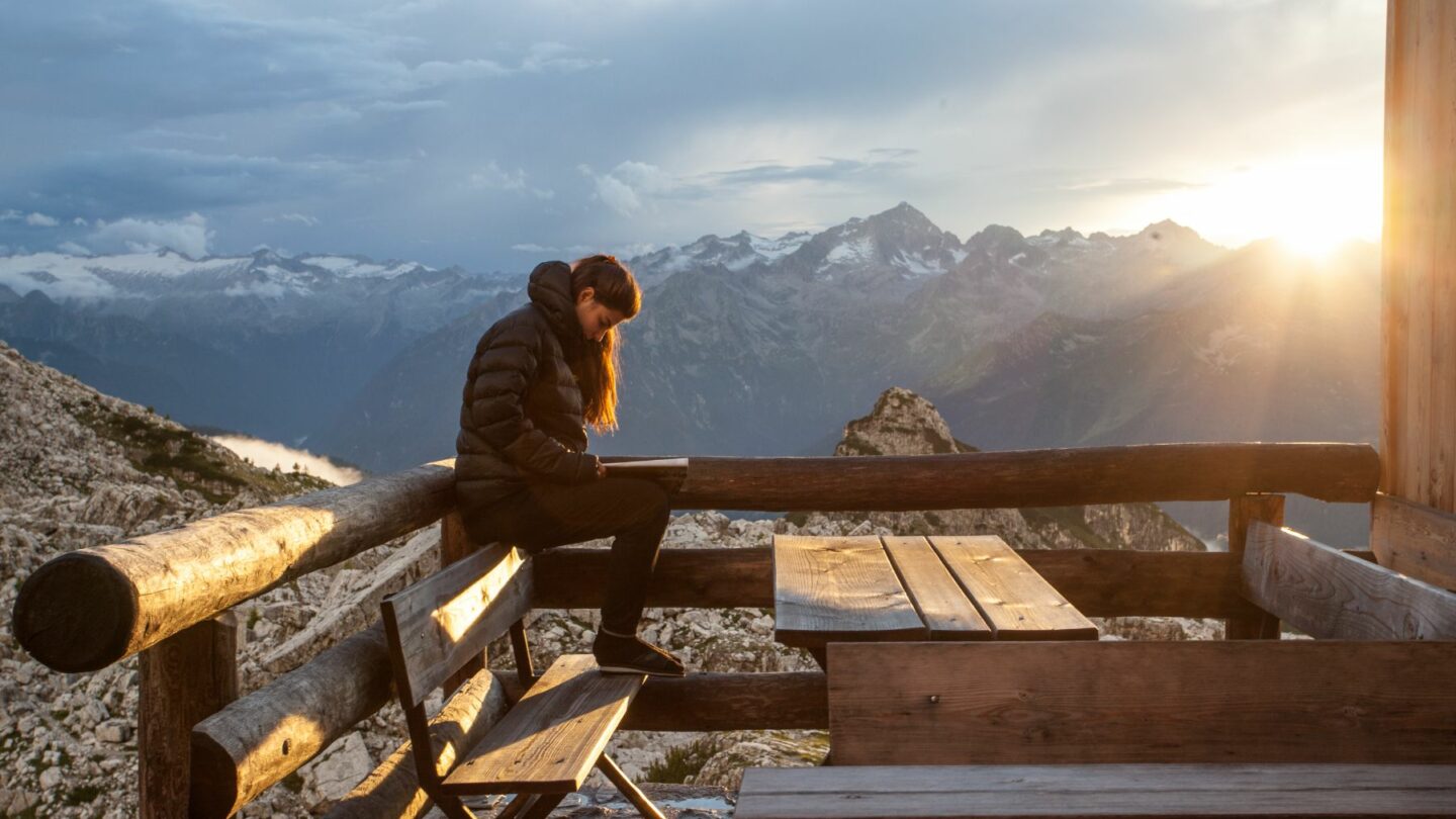 An outdoor adventurer enjoying views of the Dolomites from the Tuckett mountain hut, during sunset.