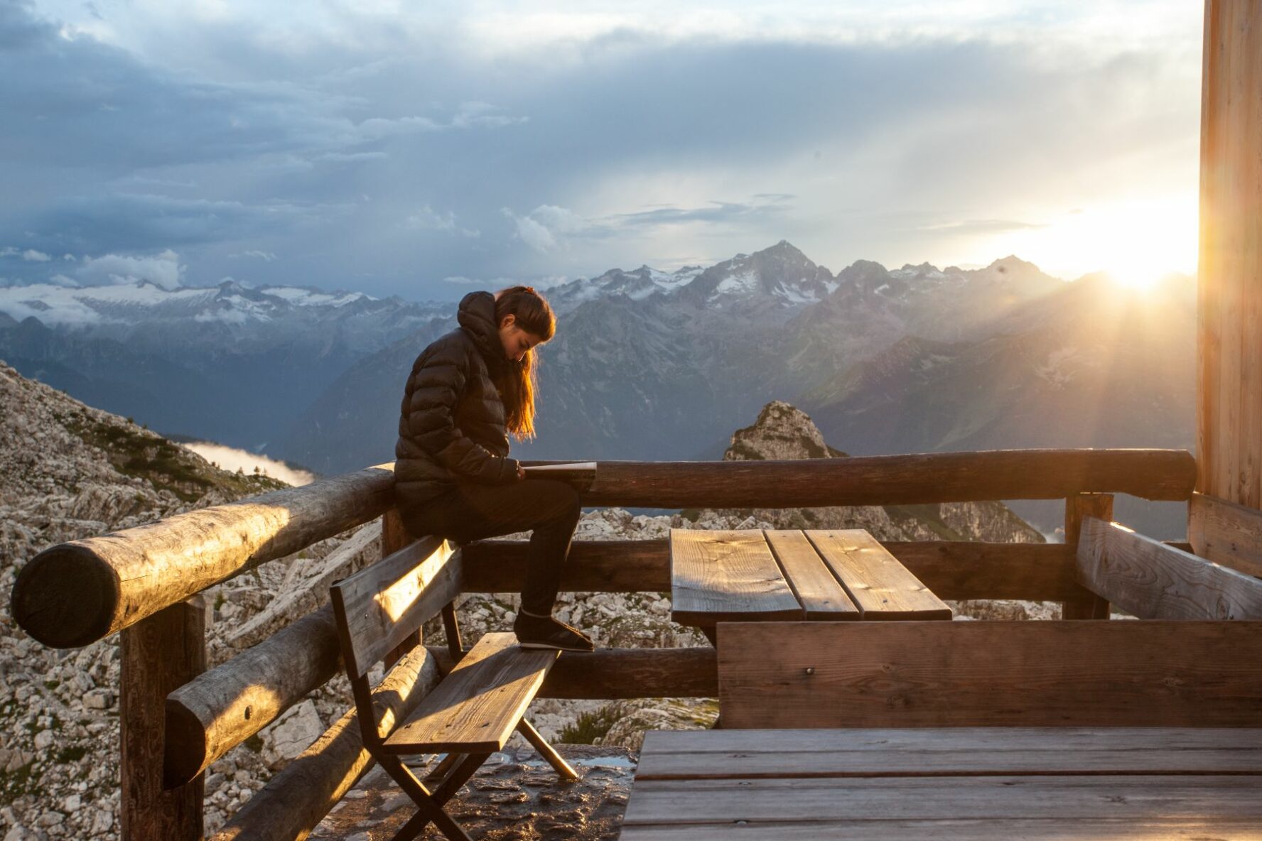 An outdoor adventurer enjoying views of the Dolomites from the Tuckett mountain hut, during sunset.