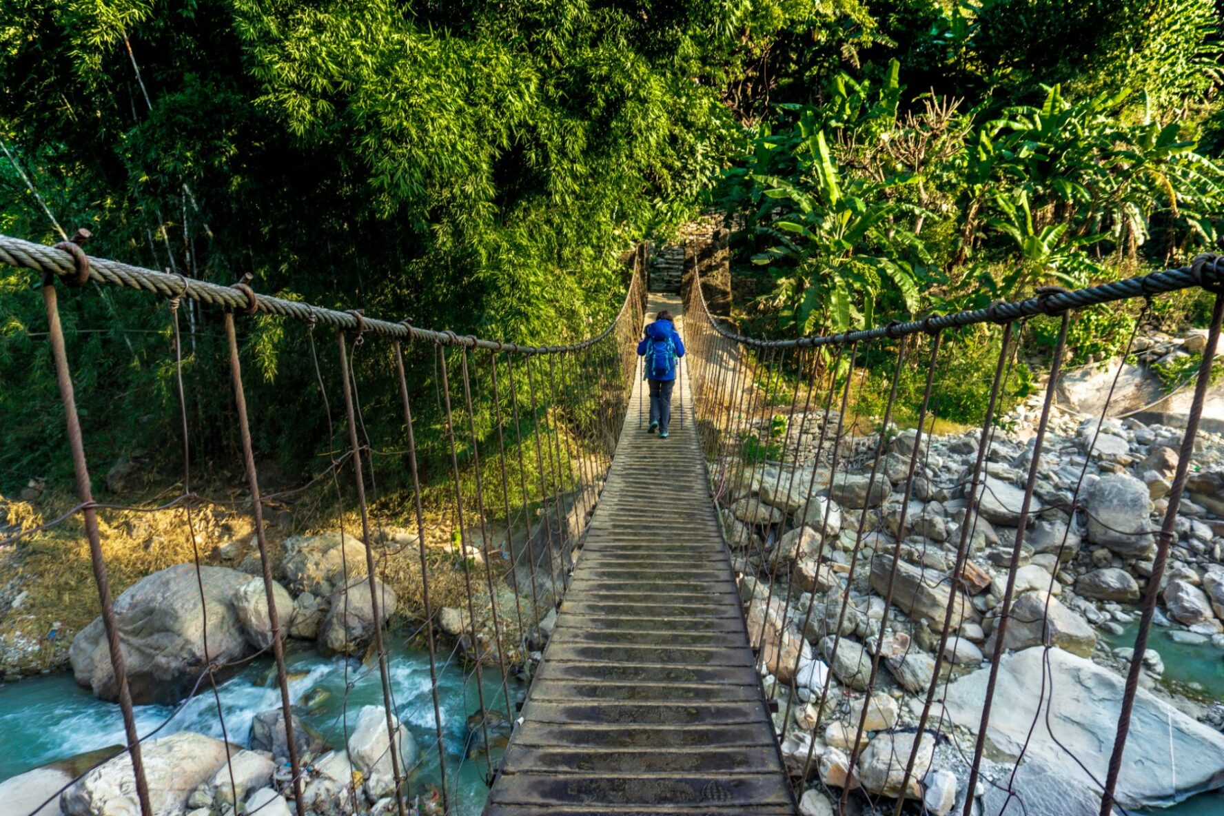Trekker crossing a suspension bridge near the Annapurna Base Camp.