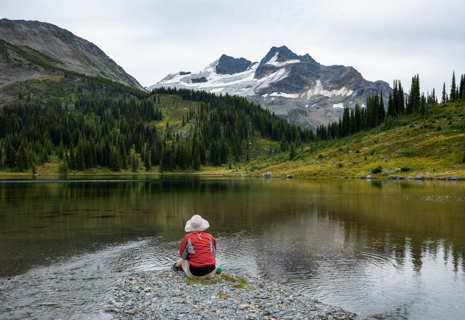 Hiker beside a lake in British Columbia, during a lodge-based hiking tour near Golden.