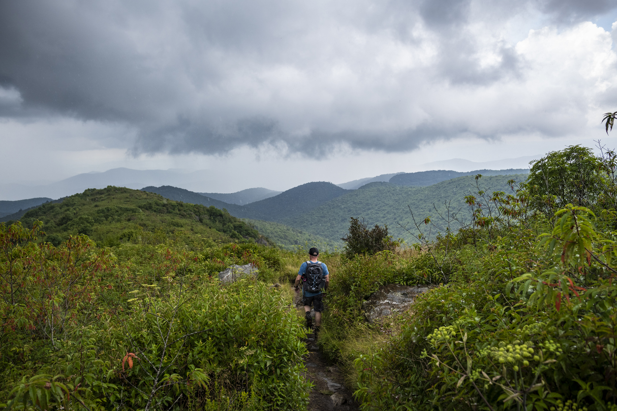 A man hikes in rain on the approximately five-mile-long Black Balsam Knob and Tennent Mountain Loop trail in Pisgah National Forest southwest of Asheville, North Carolina. The trail is accessed from the Blue Ridge Parkway. Photo taken on Tennent Mountain.