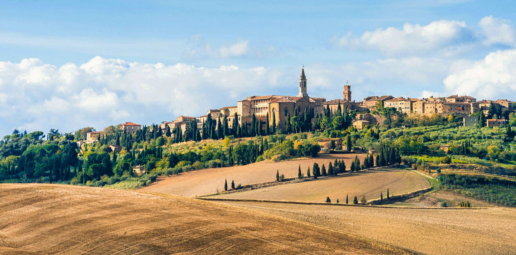 Landscape in Val d’Orcia with ochre fields and a medieval town.