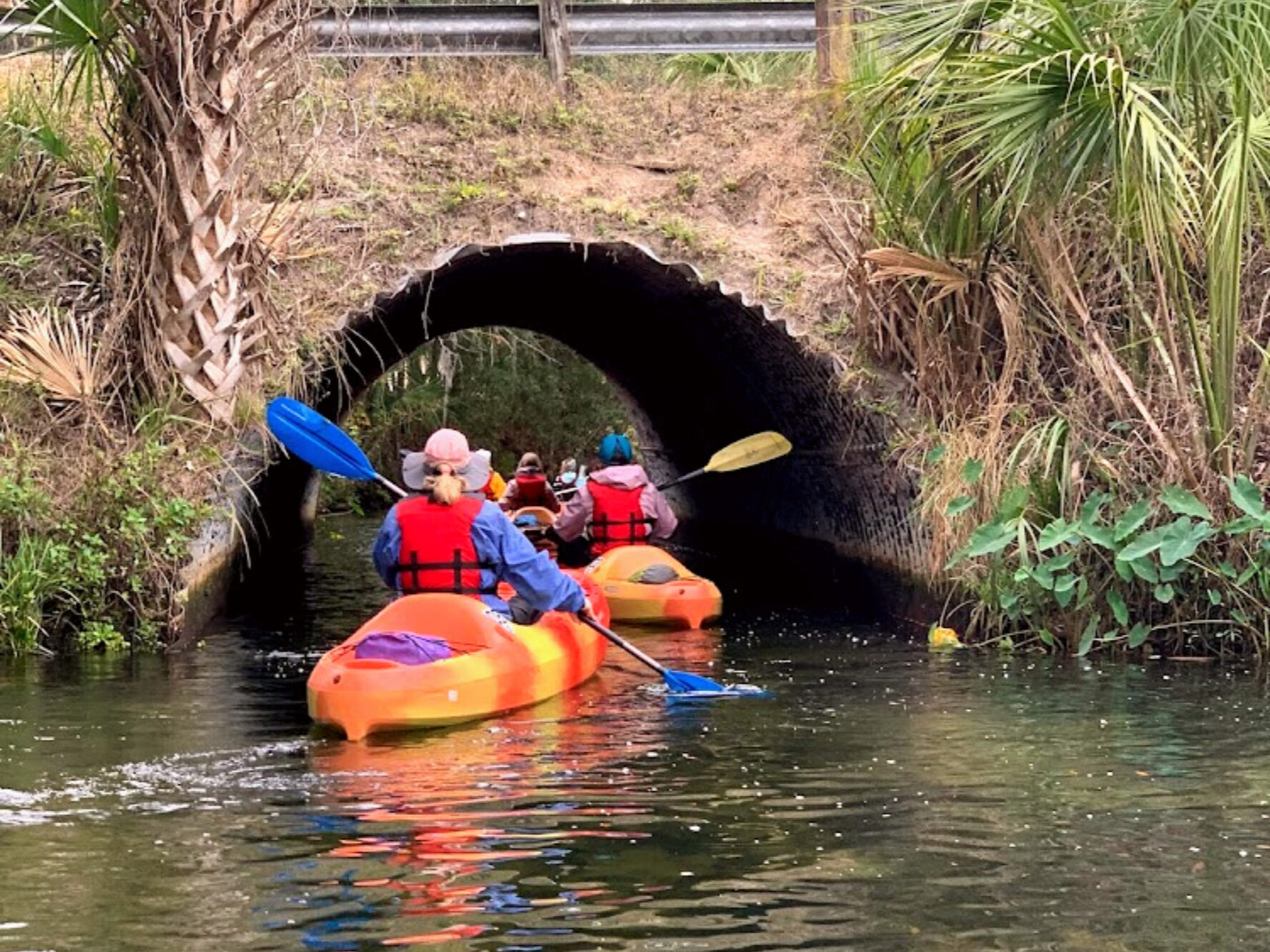 Women kayaking under a small tunnel
