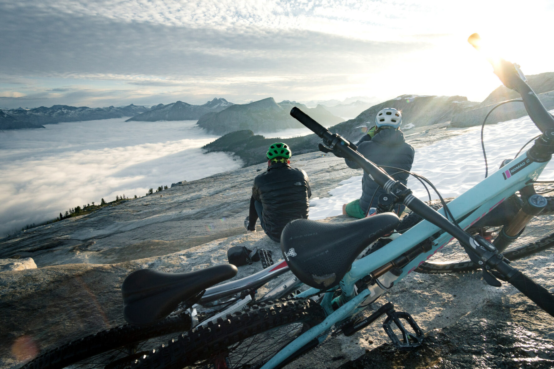 Mountain bikers looking at the views while situated above the clouds, BC’s Coast Mountains.