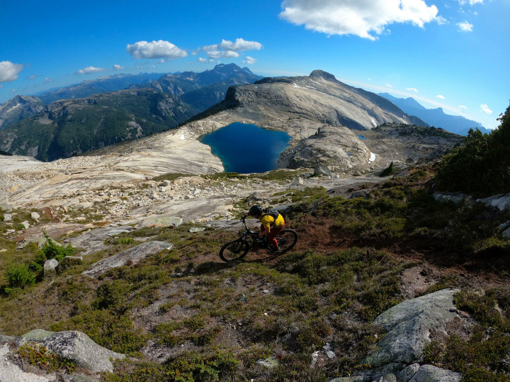 Mountain biker riding above a small lake in BC’s Coast Mountains.
