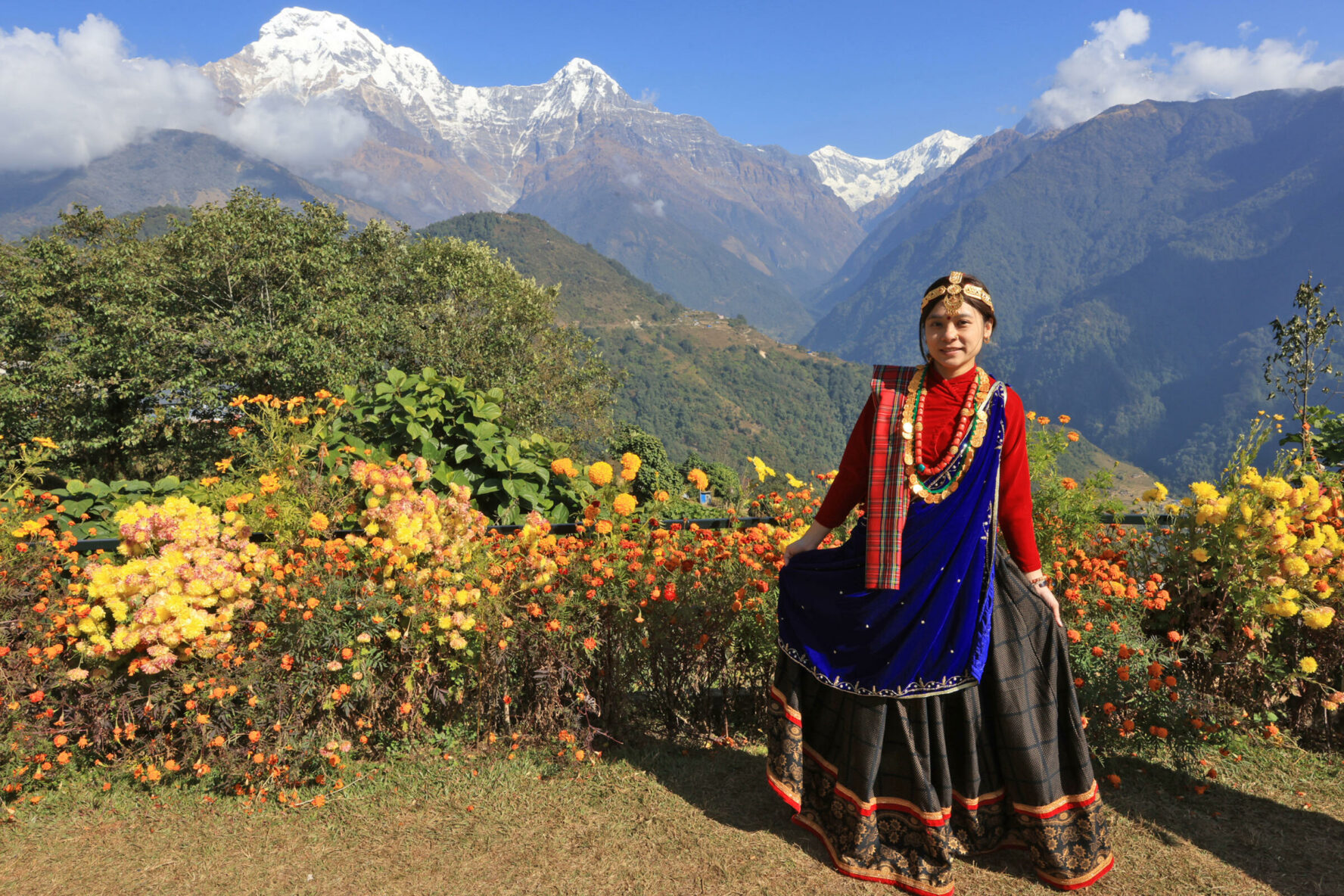 Gurung women in her traditional attire with a backdrop of Himalayan peaks, Nepal.