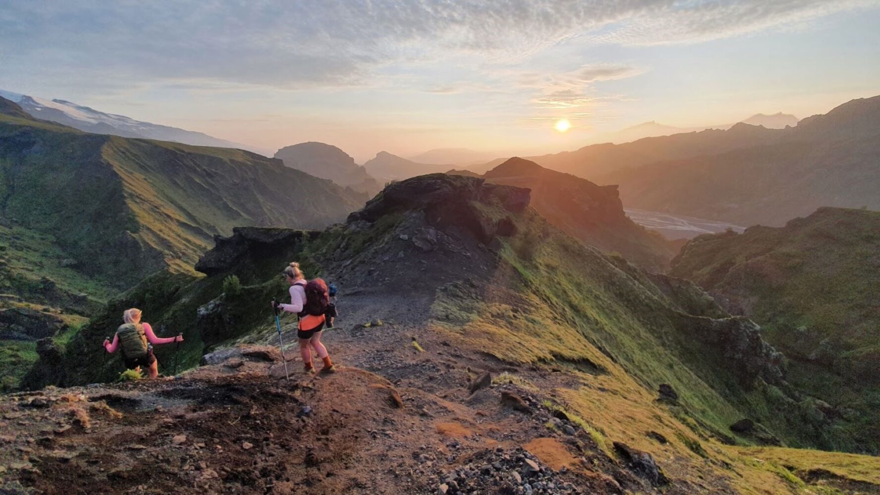 Hikers enjoying the Fimmvorduhals trail, descending a hill just before sunset.