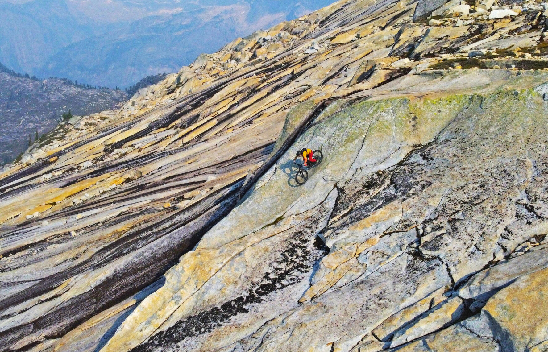 MTBer navigating near-vertical slab terrain in BC’s Coast Mountains.