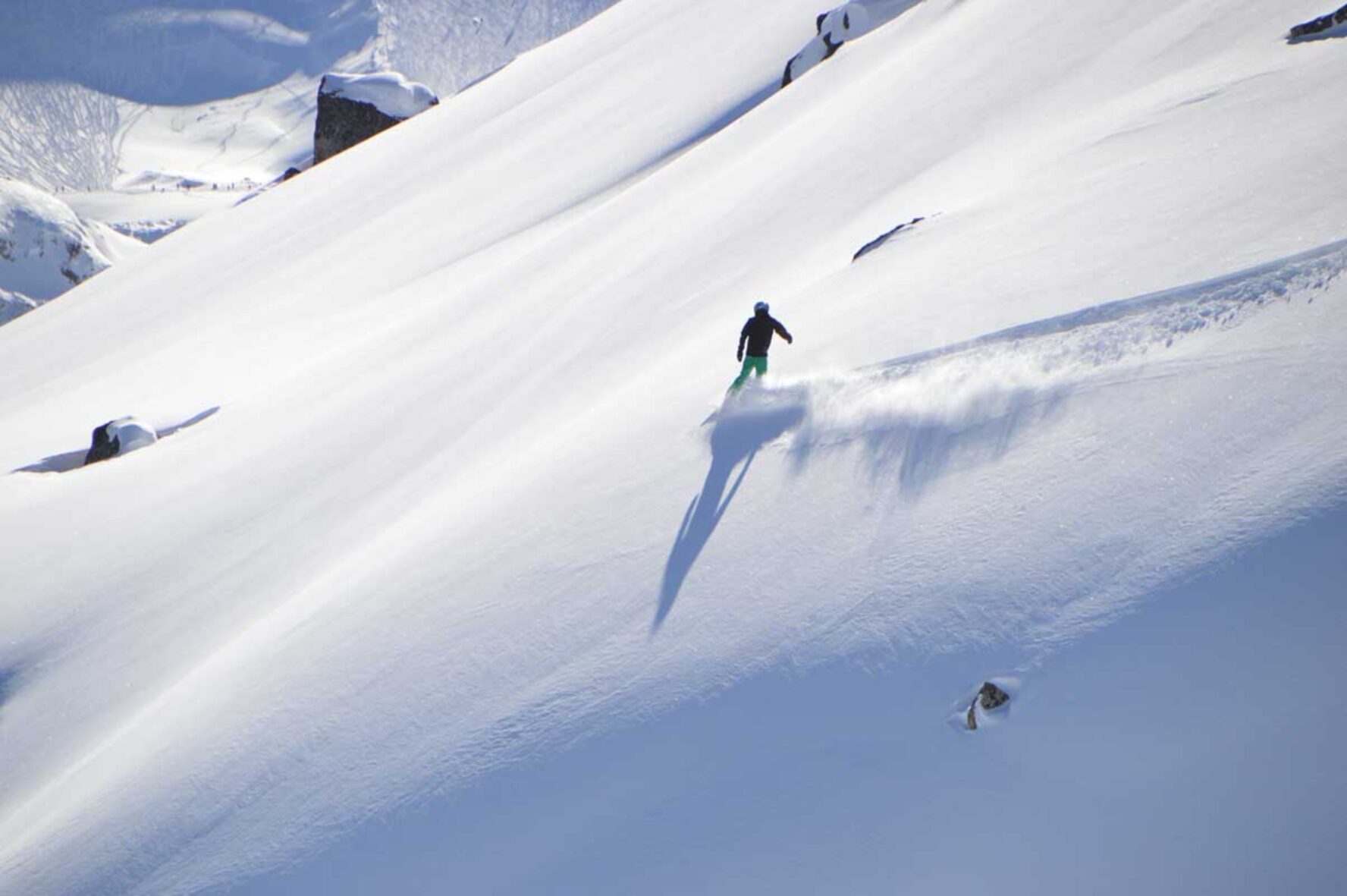 Snowboarder snowboarding in powder terrain in British Columbia, Canada.