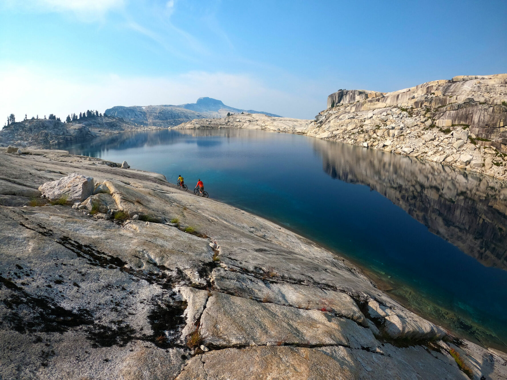 Two mountain bikers riding beside a lake in BC’s Coast Mountains.