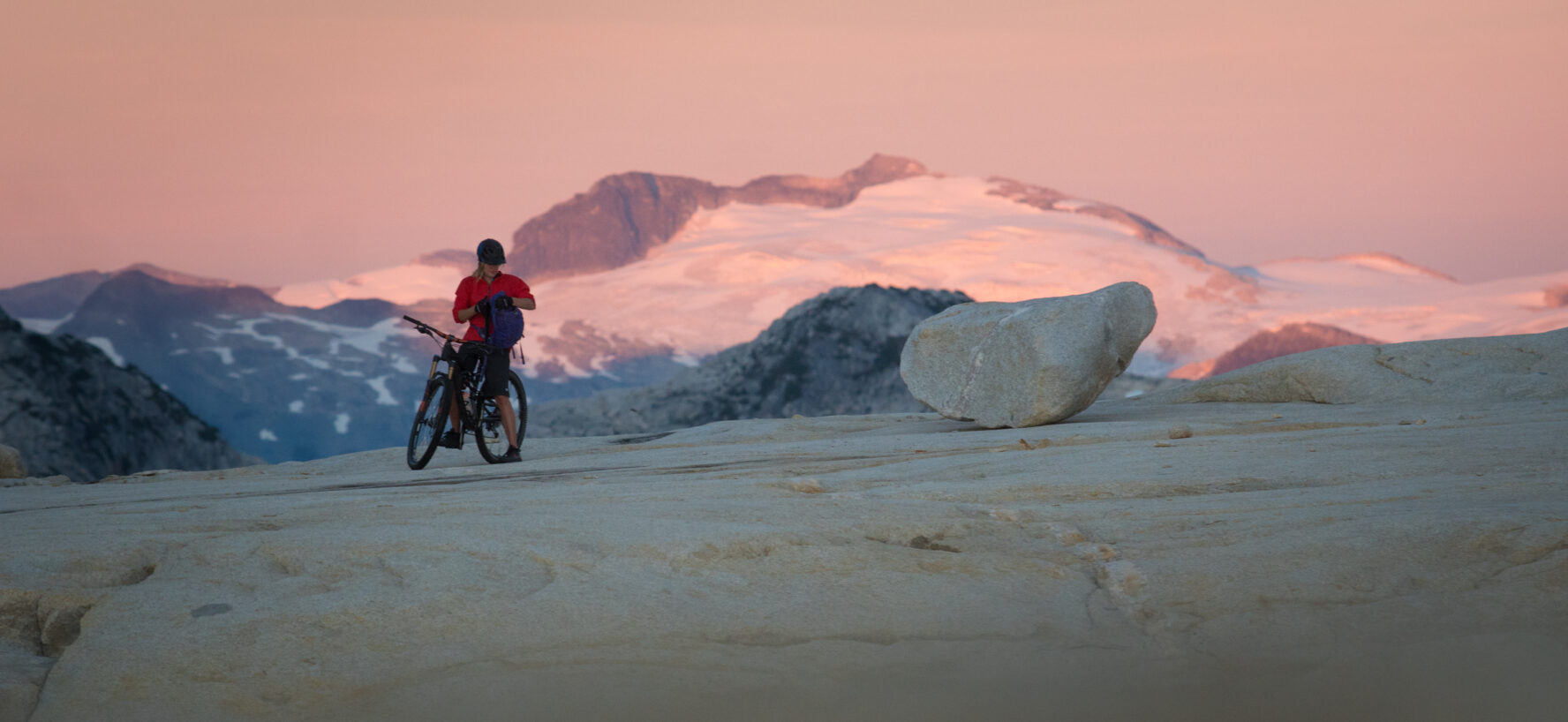 MTBer on her bike during sunset, Coast Mountains, BC.