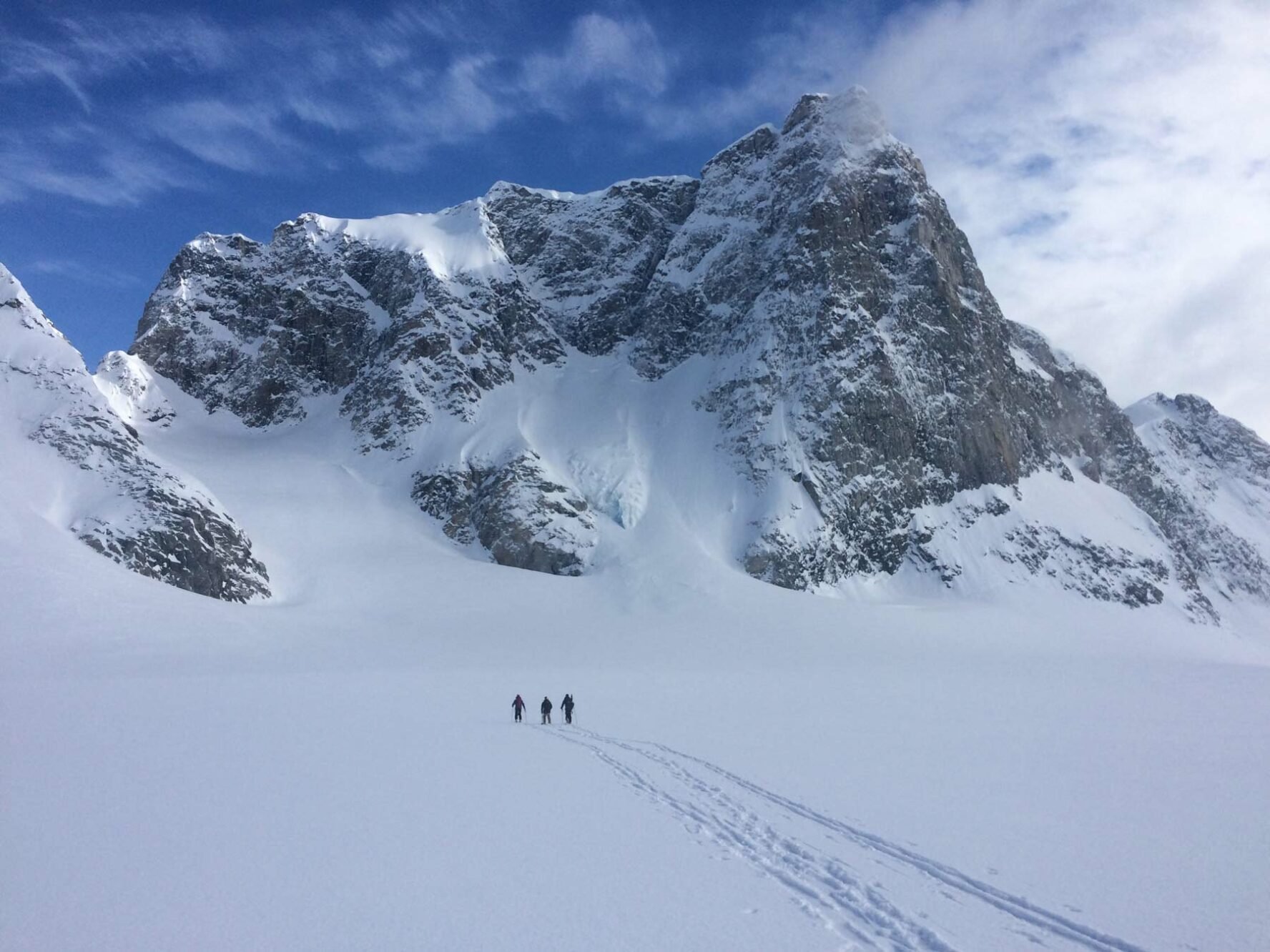 Three skiers in powder snow of Greenland