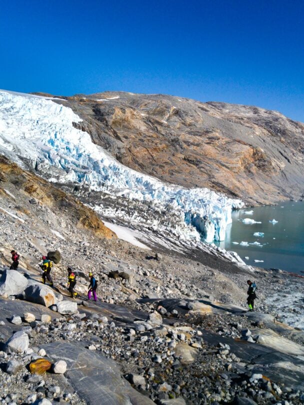 Kayakers posing near an iceberg in Greenland