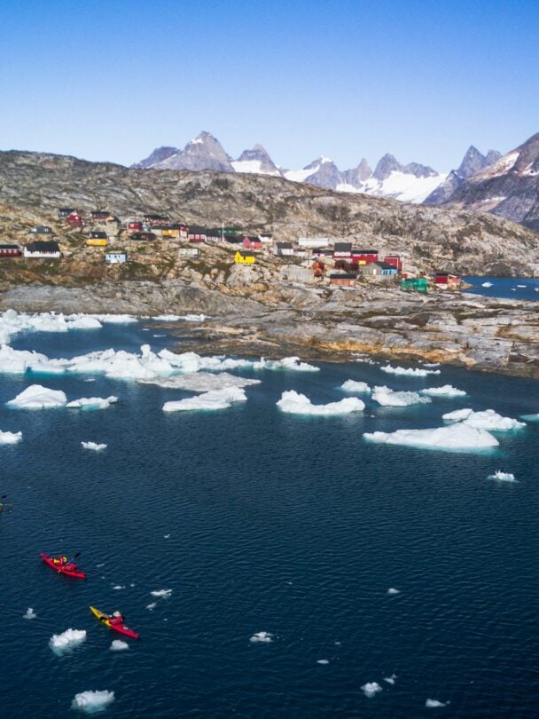 Kayakers posing near an iceberg in Greenland