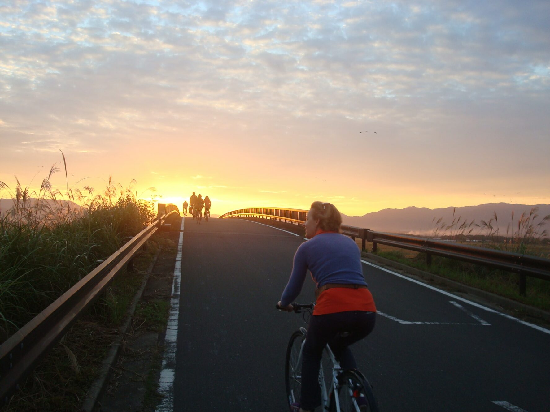 Cyclists on a road at sunset in Kyushu, Japan