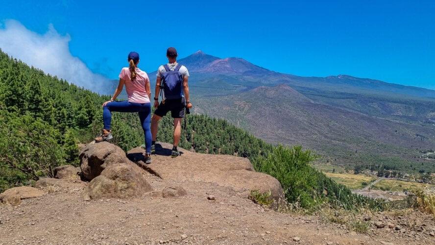 Standing couple with scenic view on volcano Pico del Teide surrounded by pine tree forest, Teno mountain, Tenerife, Canary Islands, Spain, Europe. Hiking trail from Santiago to Masca via Pico Verde