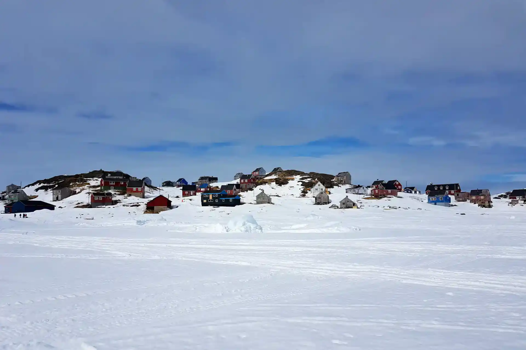 Colorful houses on a hillside in a snowy landscape in East Greenland