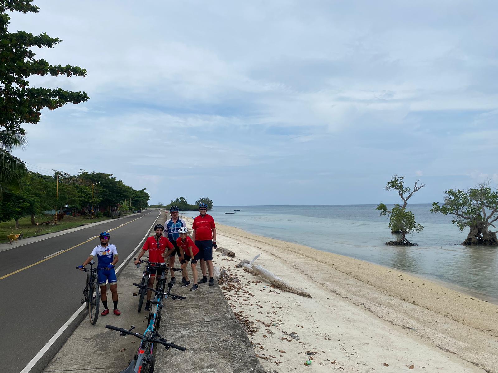 Group of cyclists on a coastal road in Siquijor, Philippines