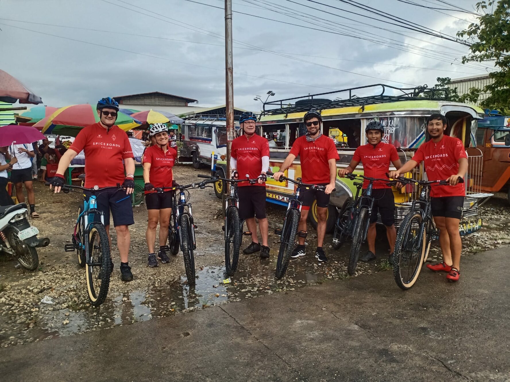 Group of cyclists in matching jerseys in front of a jeepney in the Philippines