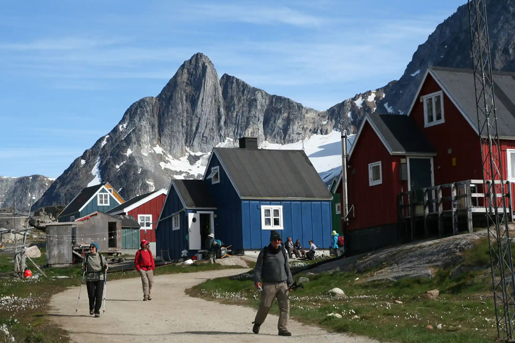 Hikers walking through a small village nestled between the mountains in Greenland