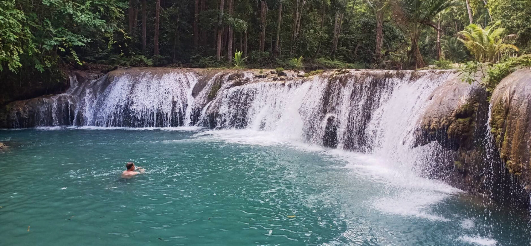 Person swimming in a natural pool near the cascades of Cambugahay Waterfall