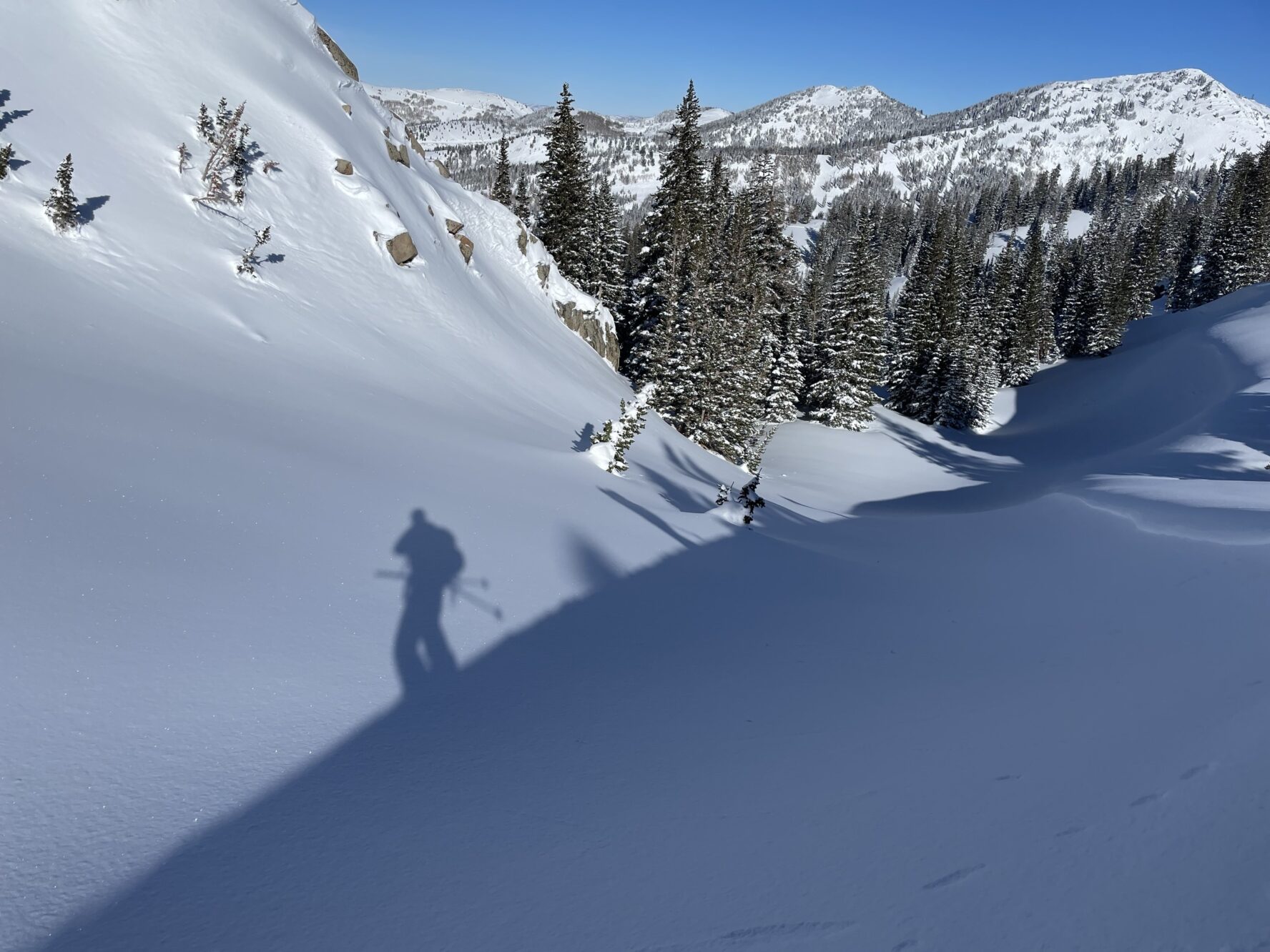 A shadow of a skier on a snowy slope with mountains in the background