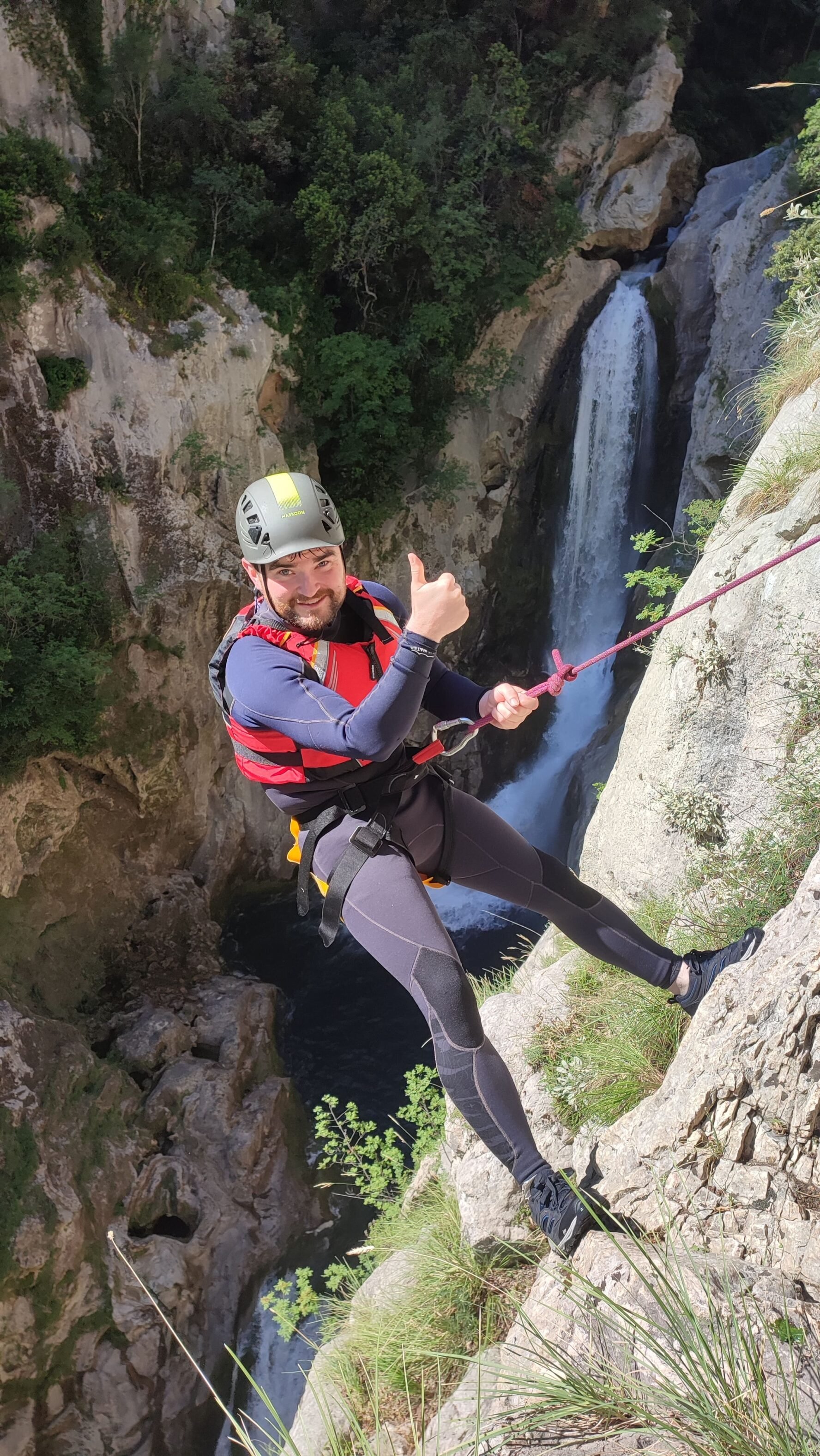 Thumbs up while abseiling near a waterfall