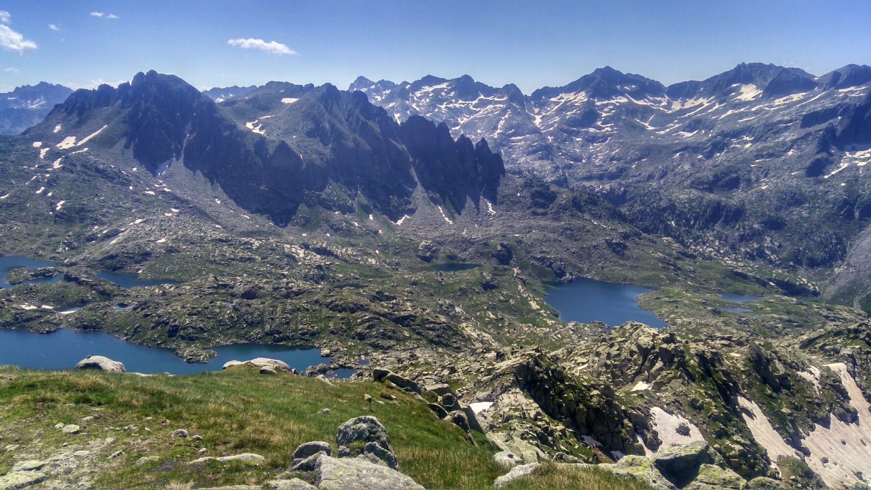 Alpine landscape in the Spanish Pyrenees with rugged mountains, snow patches, and small lakes