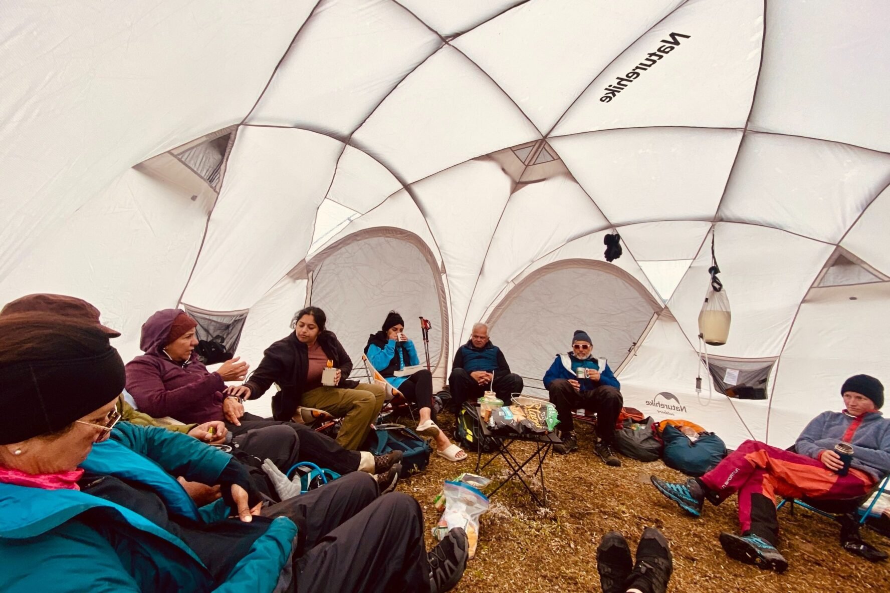 Hikers relaxing inside a spacious dome tent with camping gear