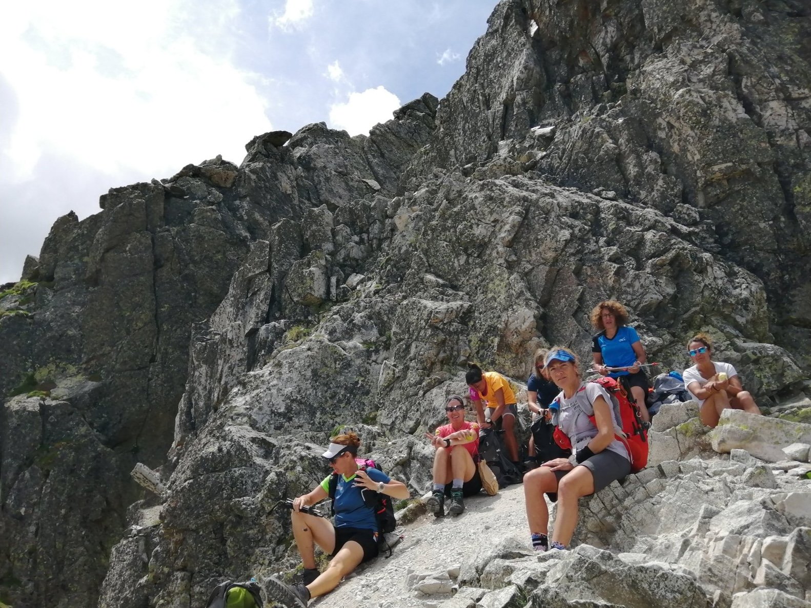 Hikers resting on rocky mountain terrain under a cloudy sky