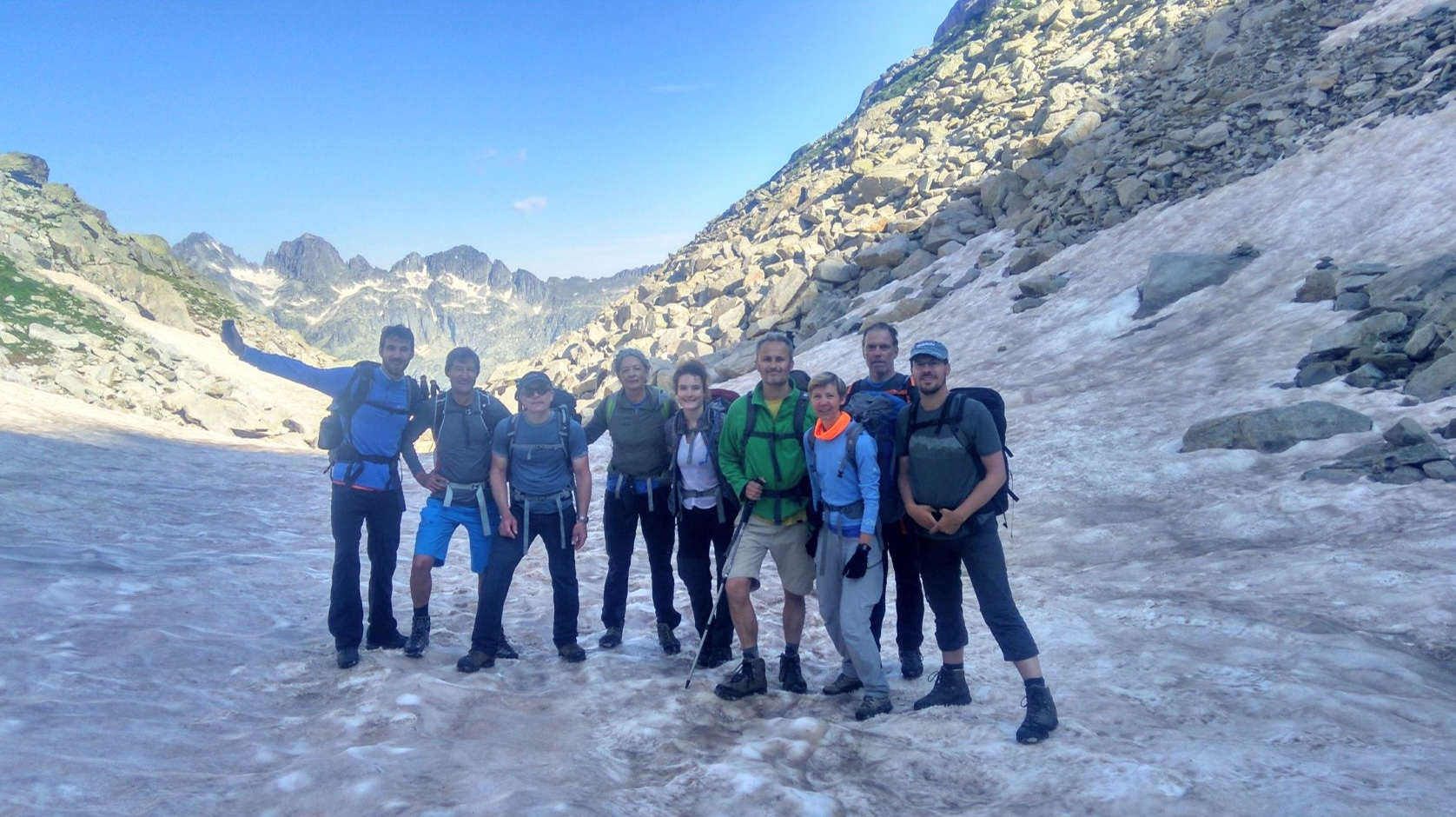 Hikers on a snowy mountain trail with rocky landscape in the background