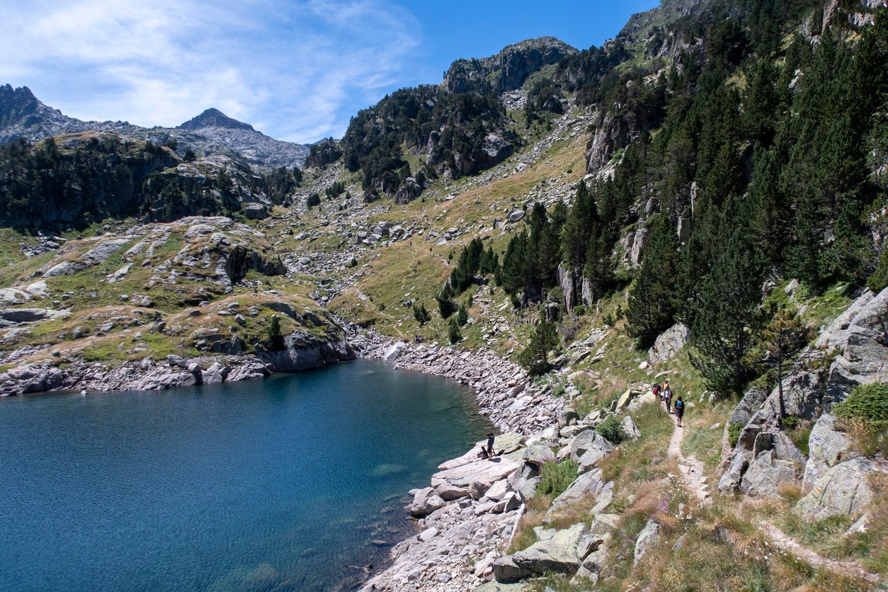 Hikers on a trail near an alpine lake in the Spanish Pyrenees