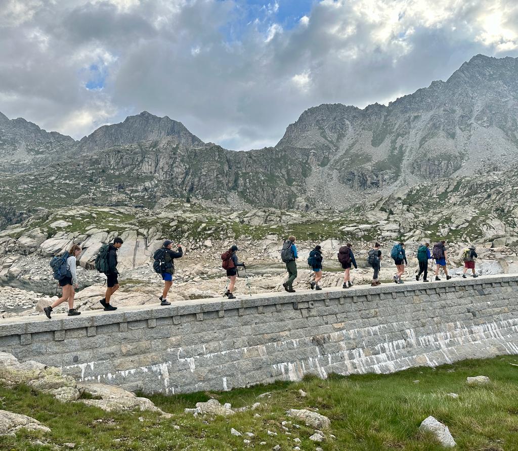 Hikers walking on a stone wall in a mountainous terrain