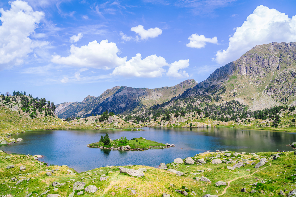 A mountain lake surrounded by mountains and green grass near Saboredo