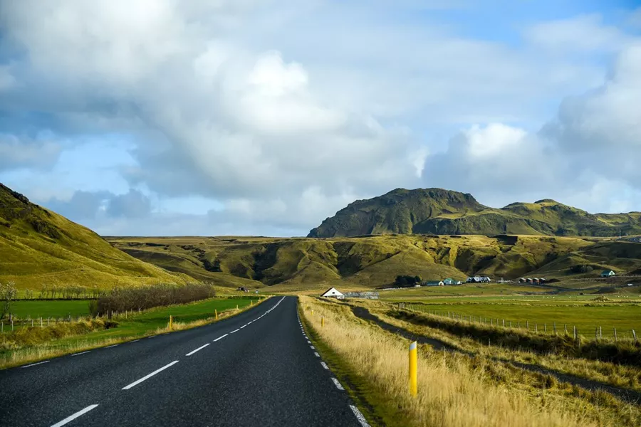 A paved road with a view of green hills in Iceland