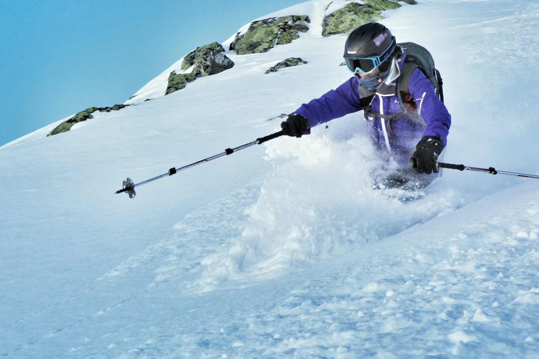 A skier in a purple jacket skiing down a snowy slope in the Verbier area