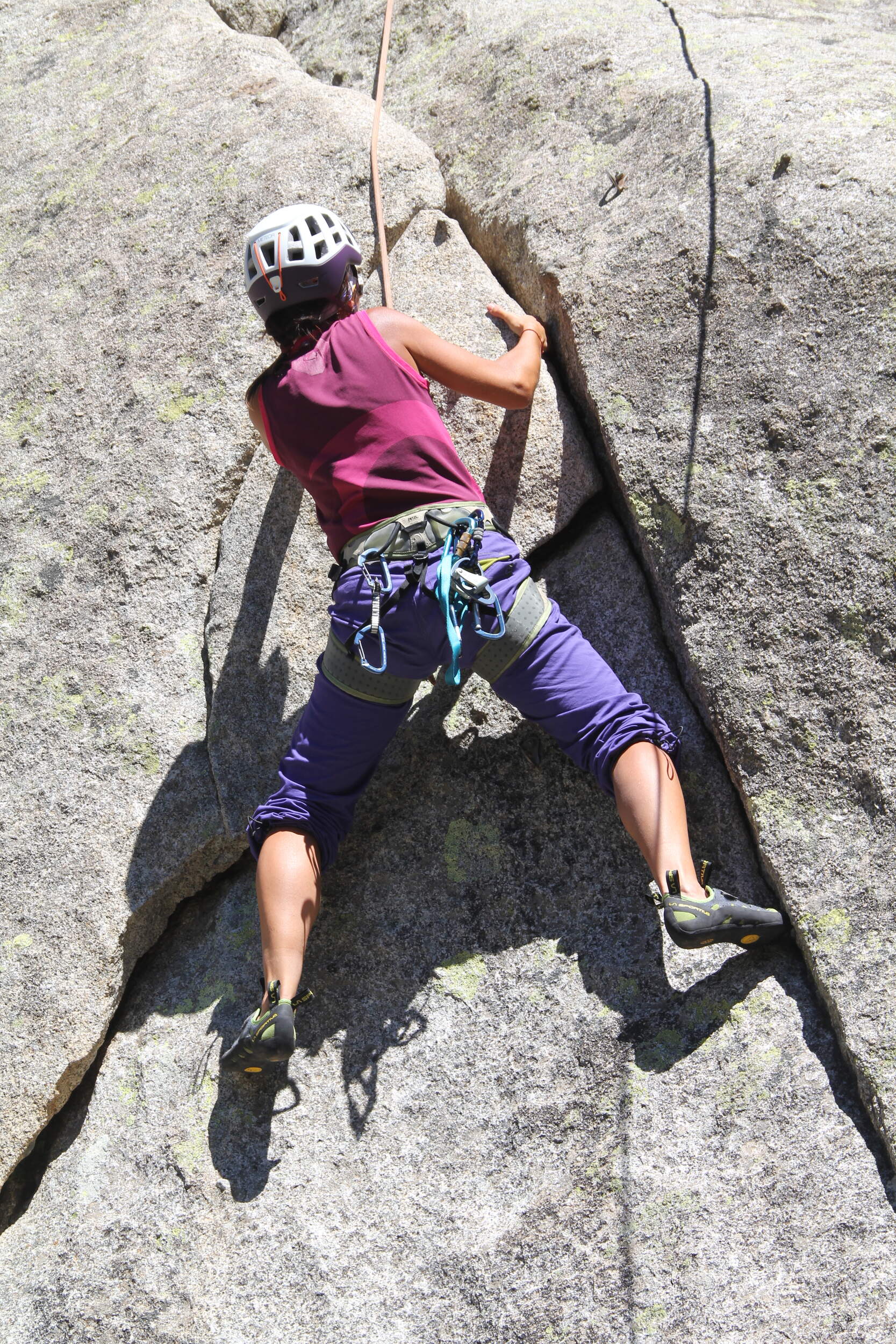Climber with gear gripping onto a steep rock face