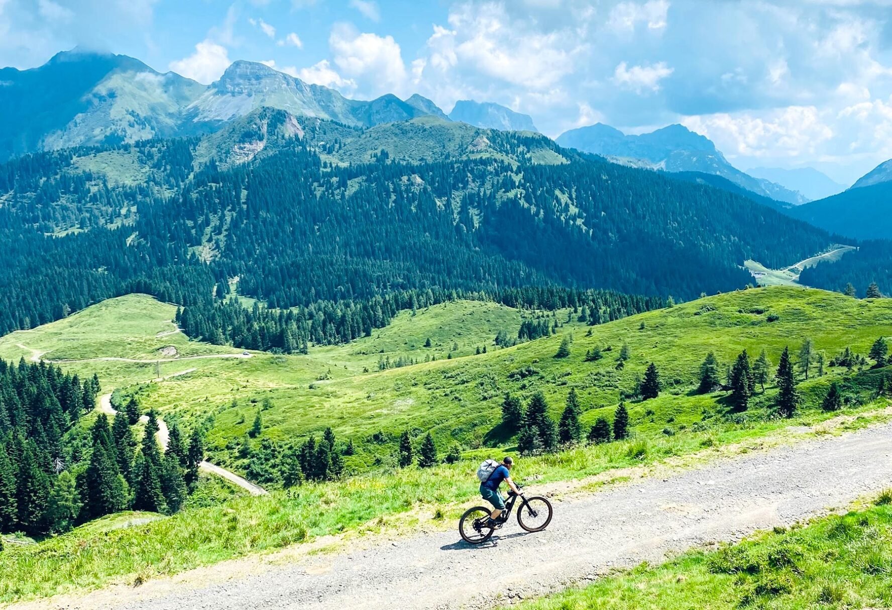 Cyclist riding on a mountain trail with lush green landscape